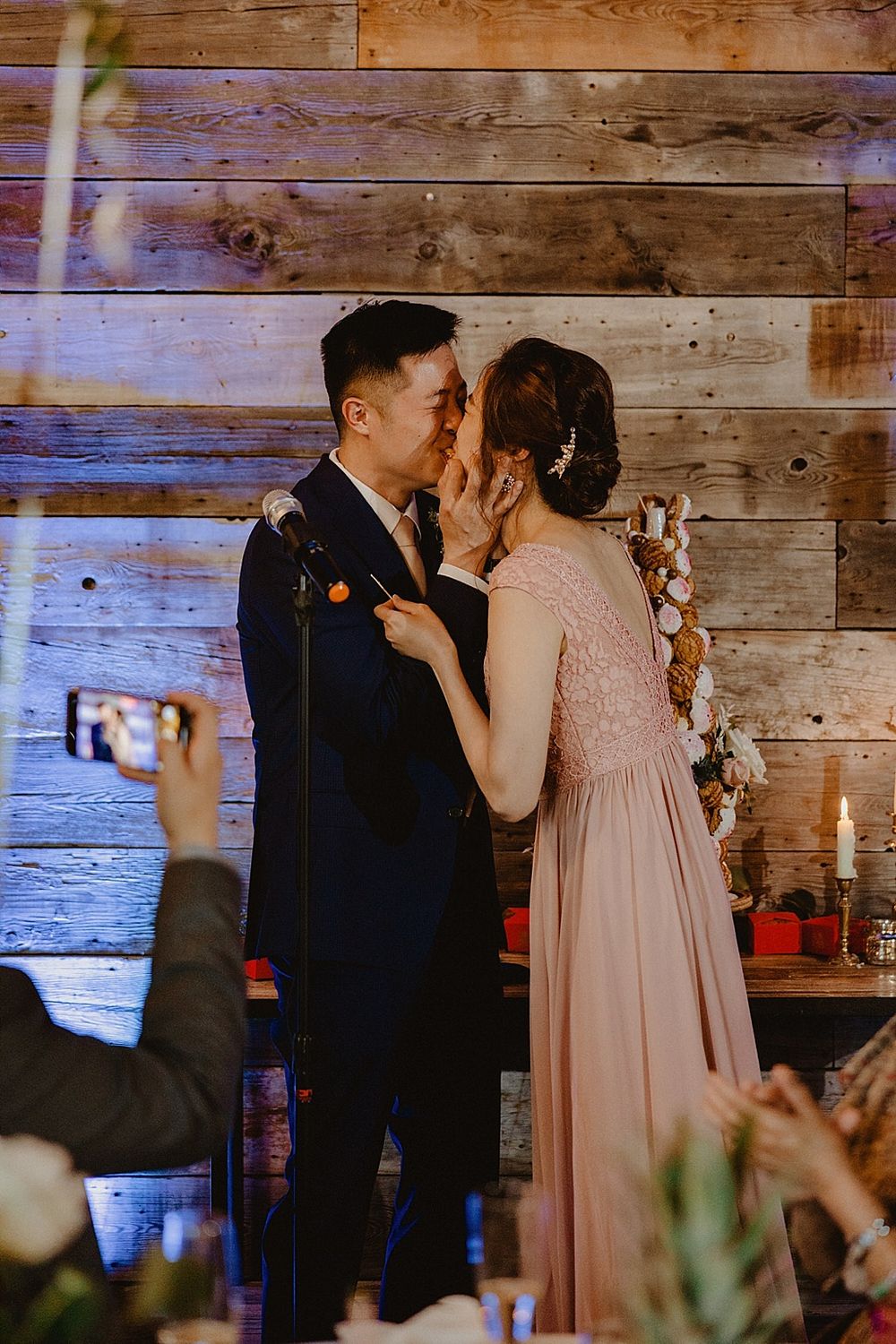 A tender dance moment captured in a rustic barn setting with wooden walls and atmospheric lighting.
