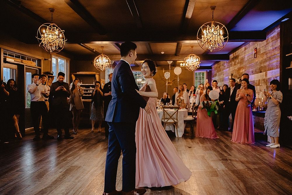 Wedding celebration in rustic venue with couples dancing under crystal chandeliers.