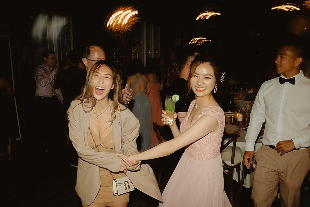 Two guests dancing together at a wedding party with warm ambient lighting.