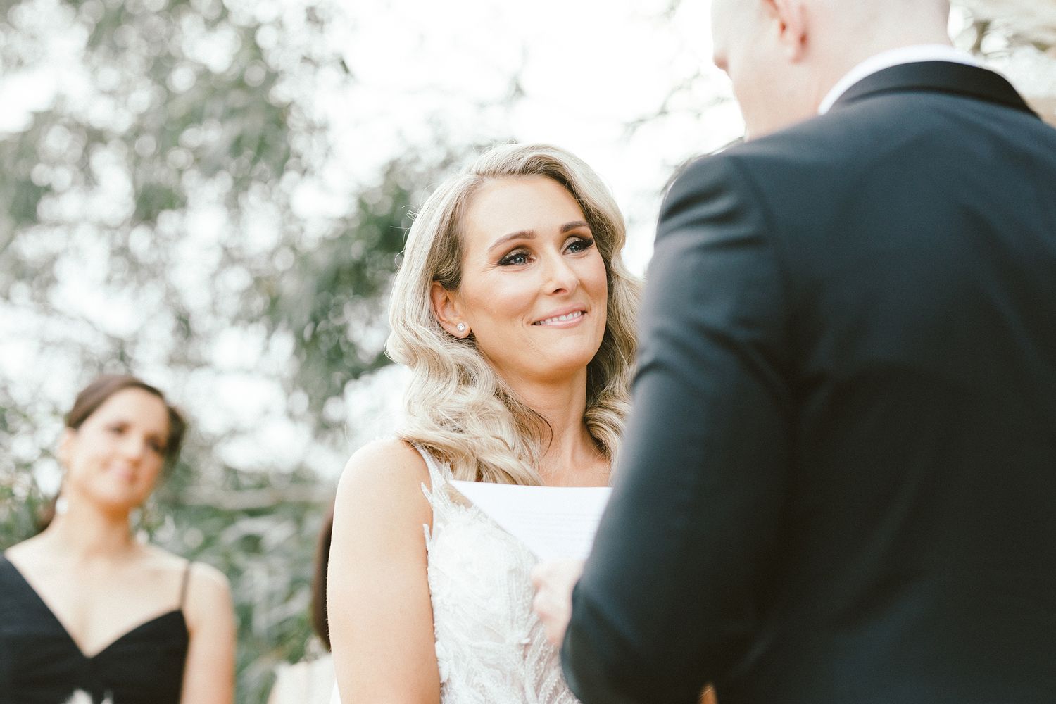 Bride and groom share a touching first look moment under trees during their wedding ceremony.