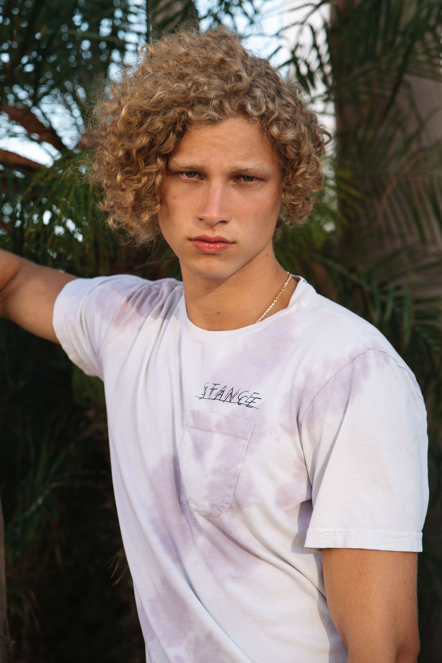 Curly blonde male model wearing tie-dye top from Stance, San Clemente beach fashion editorial