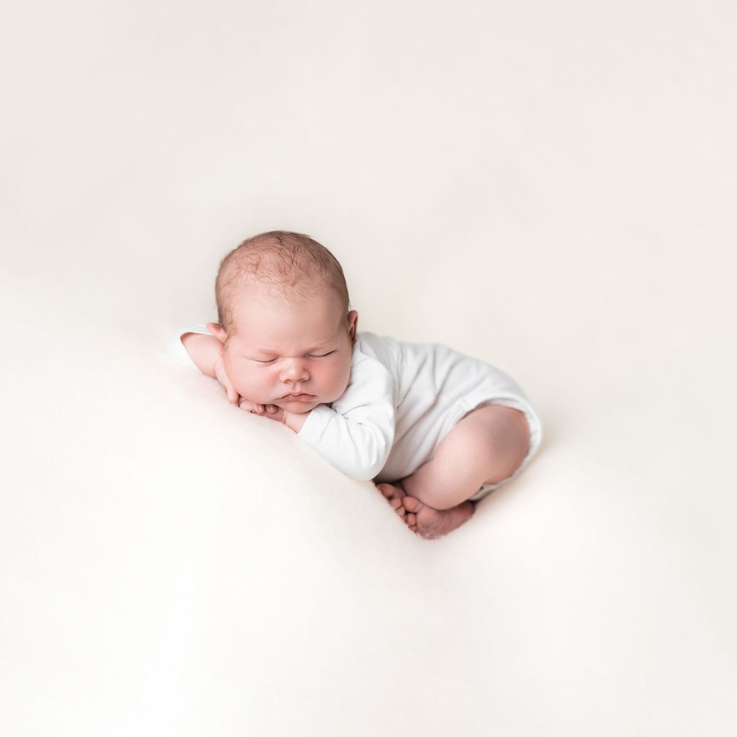 nyfødt gutt sover i fotostudio