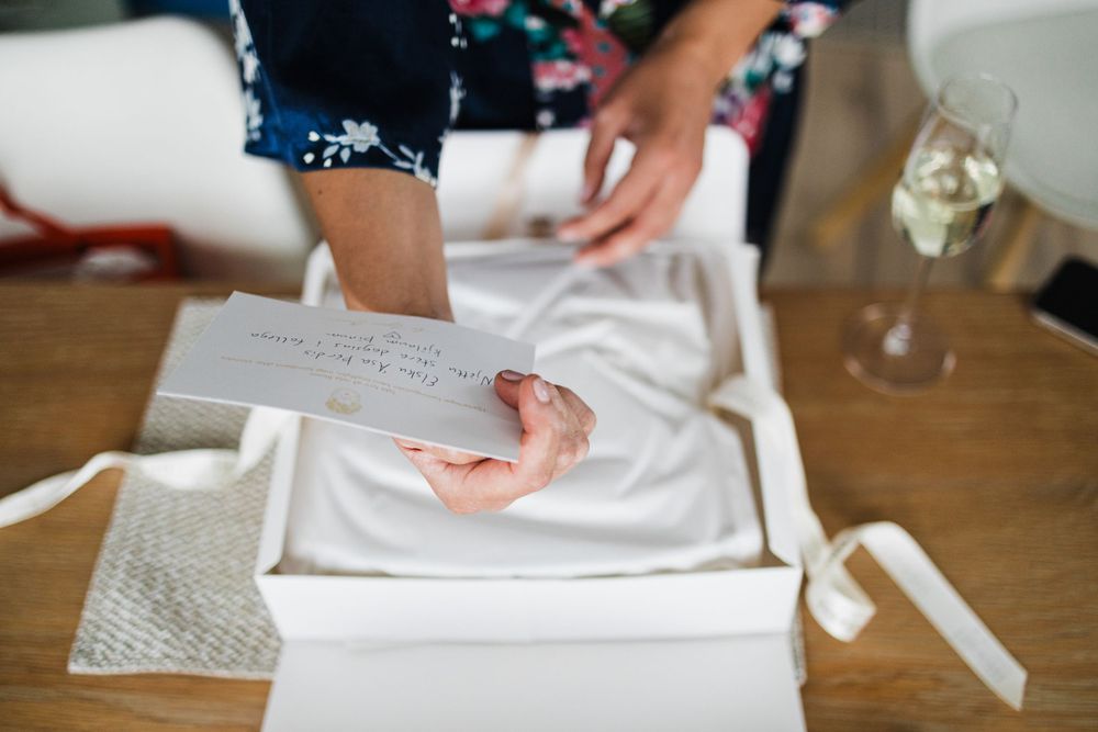 Close-up of hands unboxing or packaging a white garment with tissue paper.