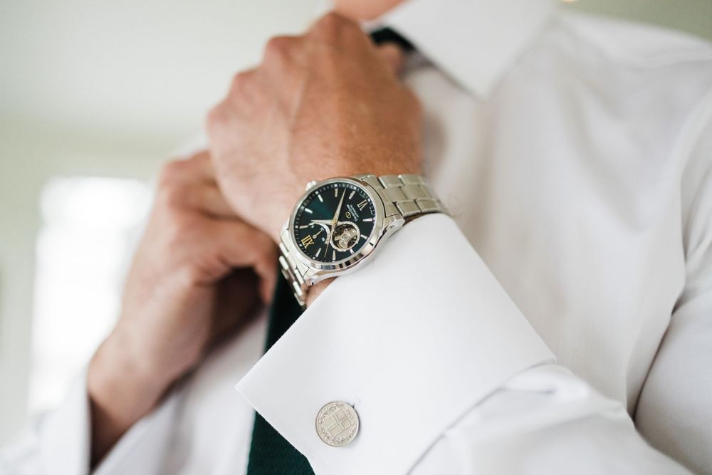Close-up of luxury watch and white shirt cuff with cufflink.
