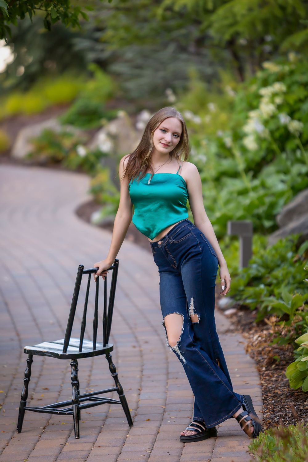 Summer senior girl standing with chair outside