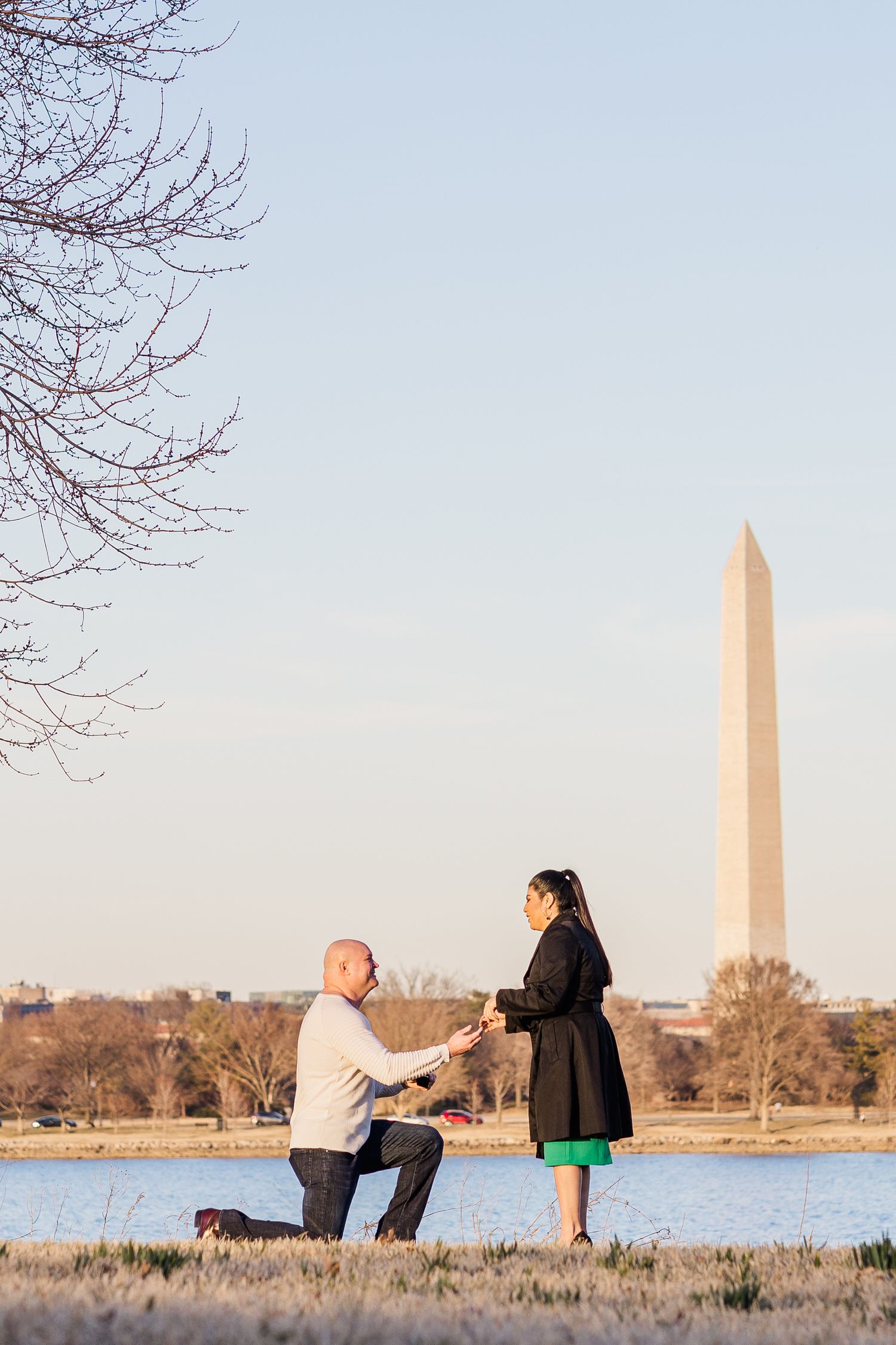 Couple sitting by the Washington Monument during sunset with water in background.