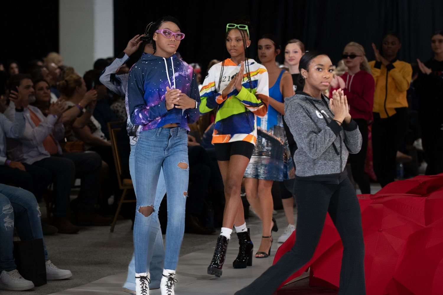 Group of performers dancing and posing energetically on fashion show runway.