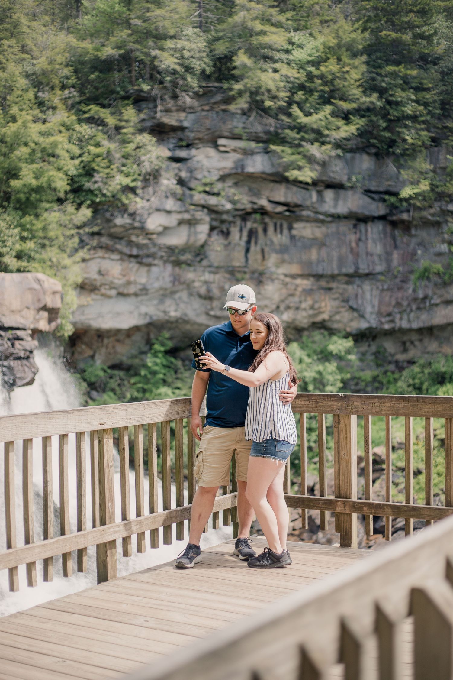 Romantic proposal moment captured on scenic waterfall overlook deck.