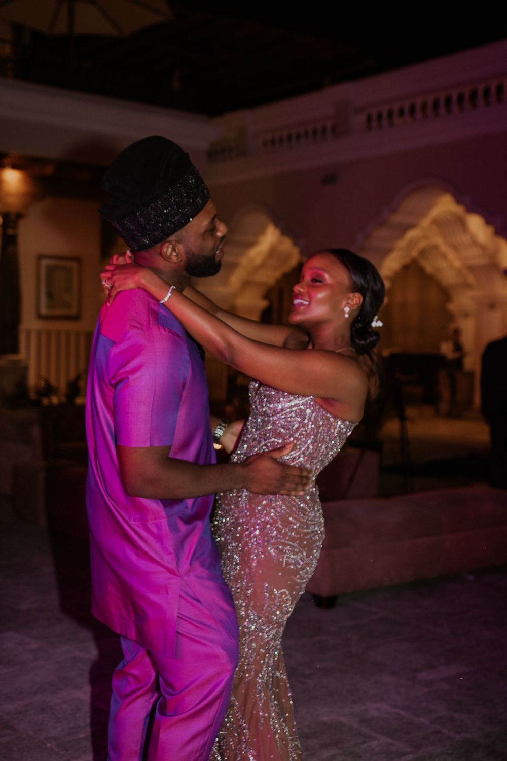 A couple dancing at their wedding reception, with the groom in pink and bride in a sparkly dress.
