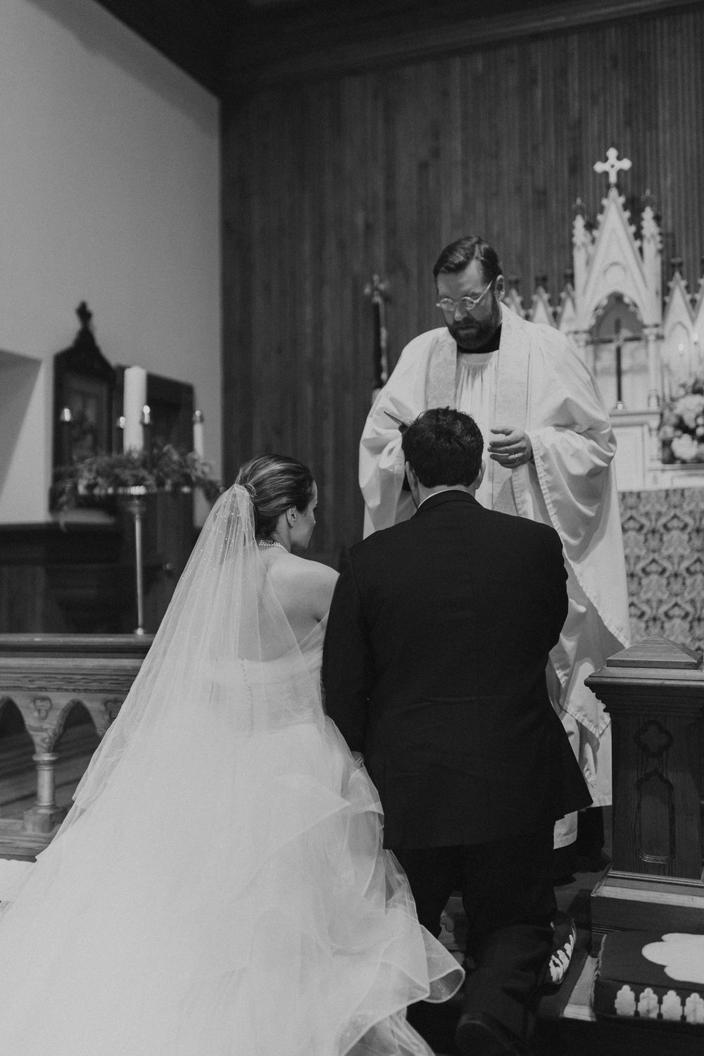 Black and white photo of wedding ceremony with clergy performing traditional blessing.