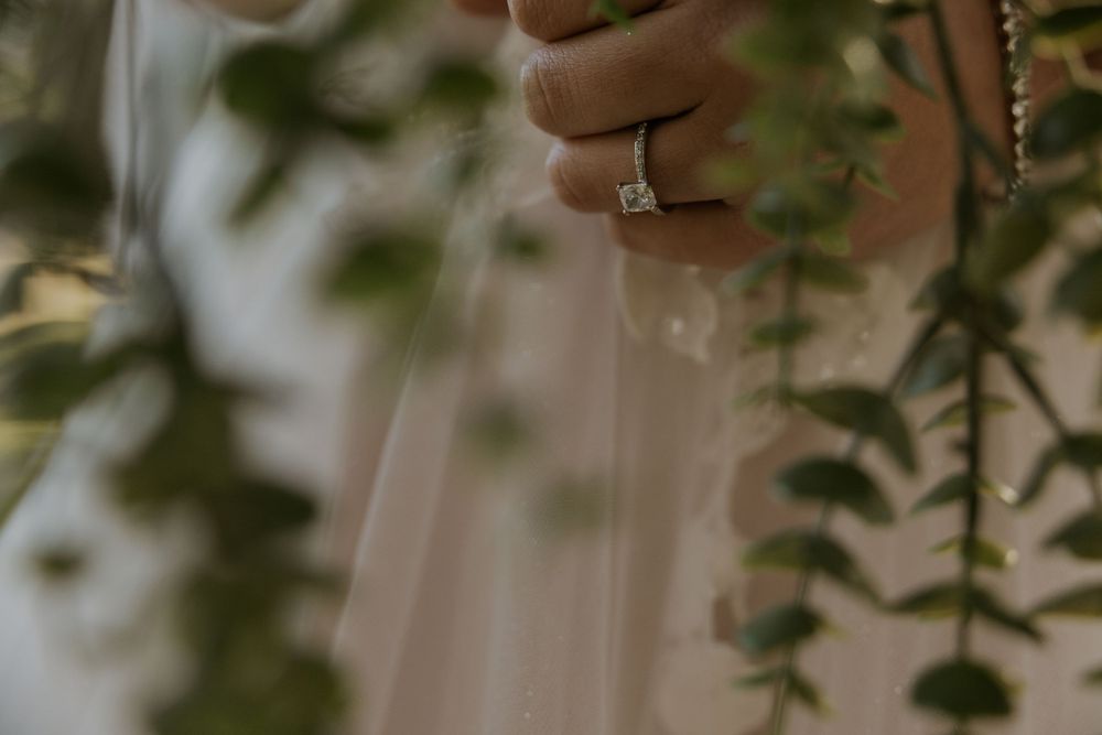 Close-up shot of an elegant engagement ring with greenery in the background.
