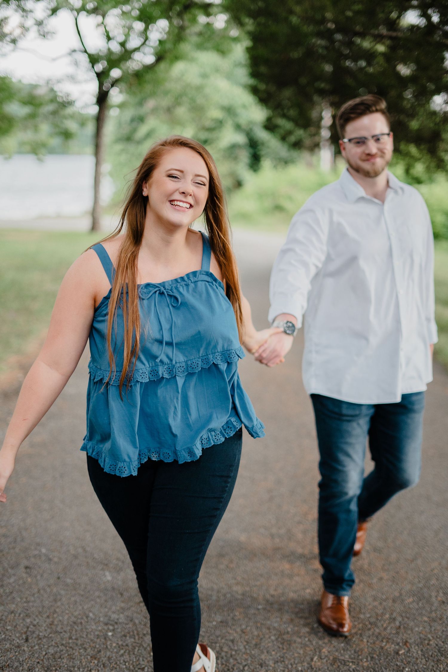 A joyful couple walking together on a peaceful tree-lined path.