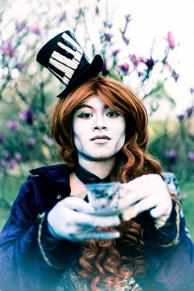 Whimsical portrait featuring a tiny piano hat and teacup in a dreamy garden setting.