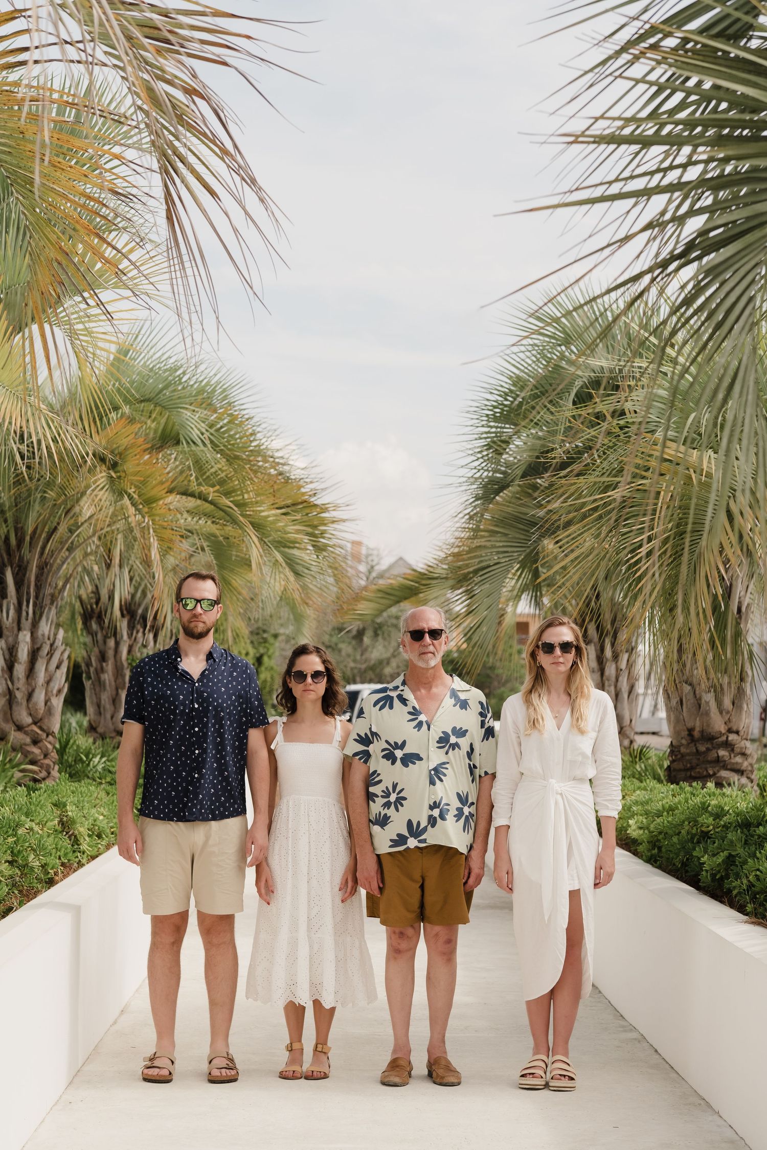 Group photo of people in coordinated beach attire standing on a palm-lined path.