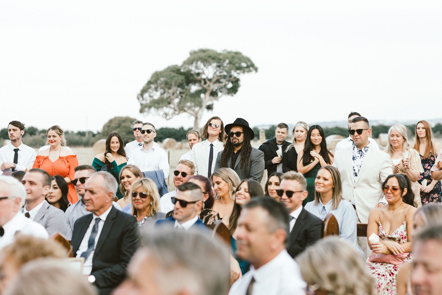 Large crowd of wedding guests seated outdoors watching the ceremony unfold.
