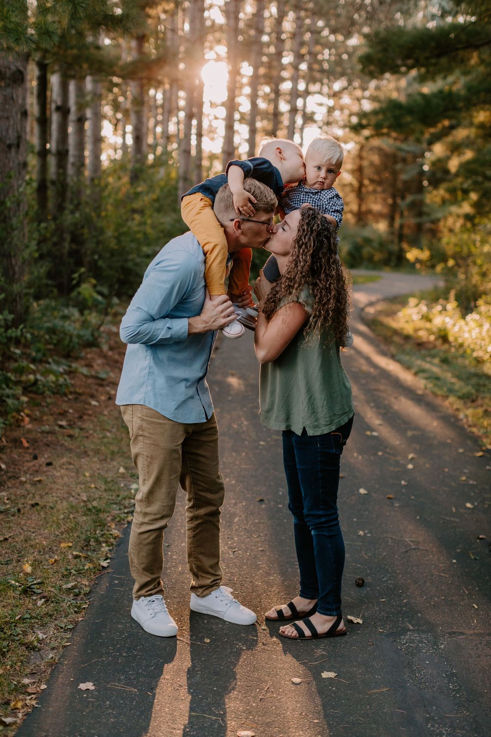 Family sharing a tender moment together on a sunlit forest path at golden hour.