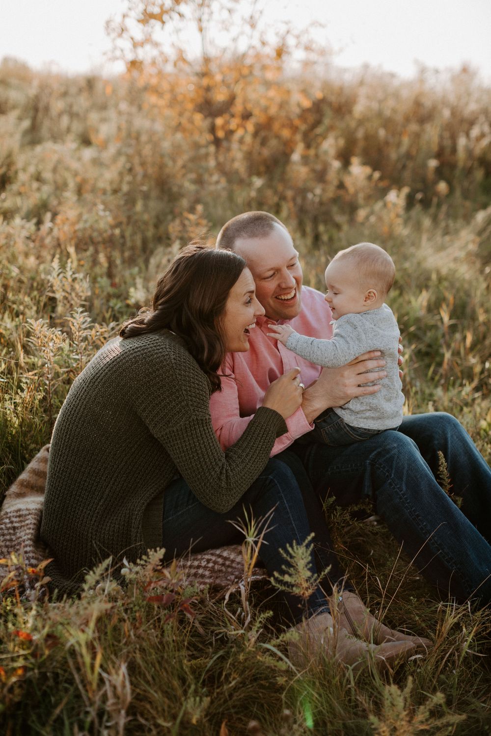 A candid family moment captured in a sunlit field during golden hour.
