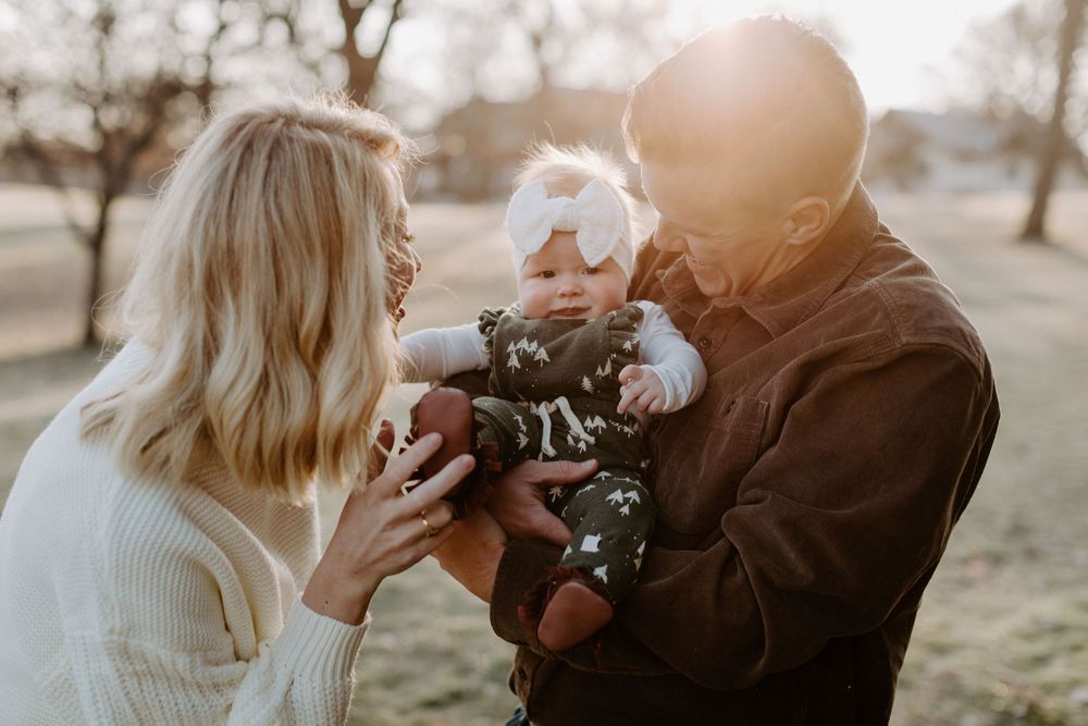 A couple shares an intimate moment outdoors while bundled in cozy sweaters during golden hour.