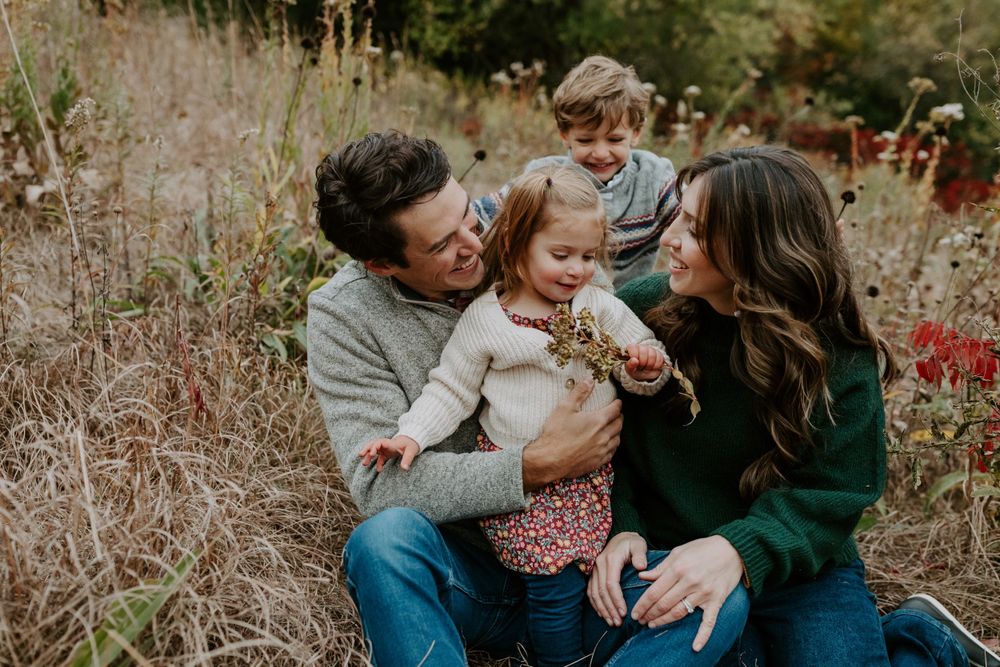 A joyful family sharing laughter and embraces while sitting together in a rustic autumn field.