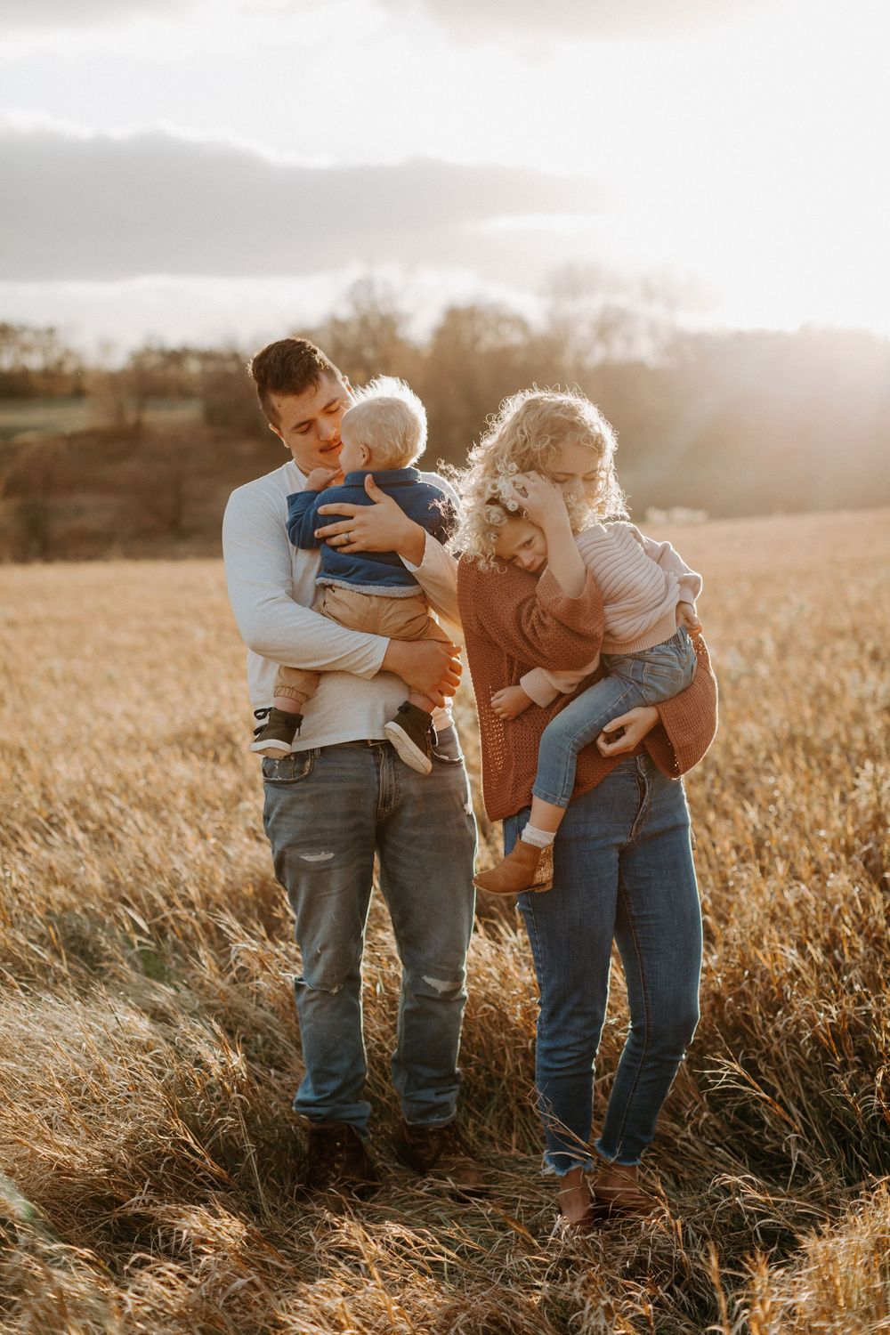 Family enjoying a tender moment together in golden field at sunset.