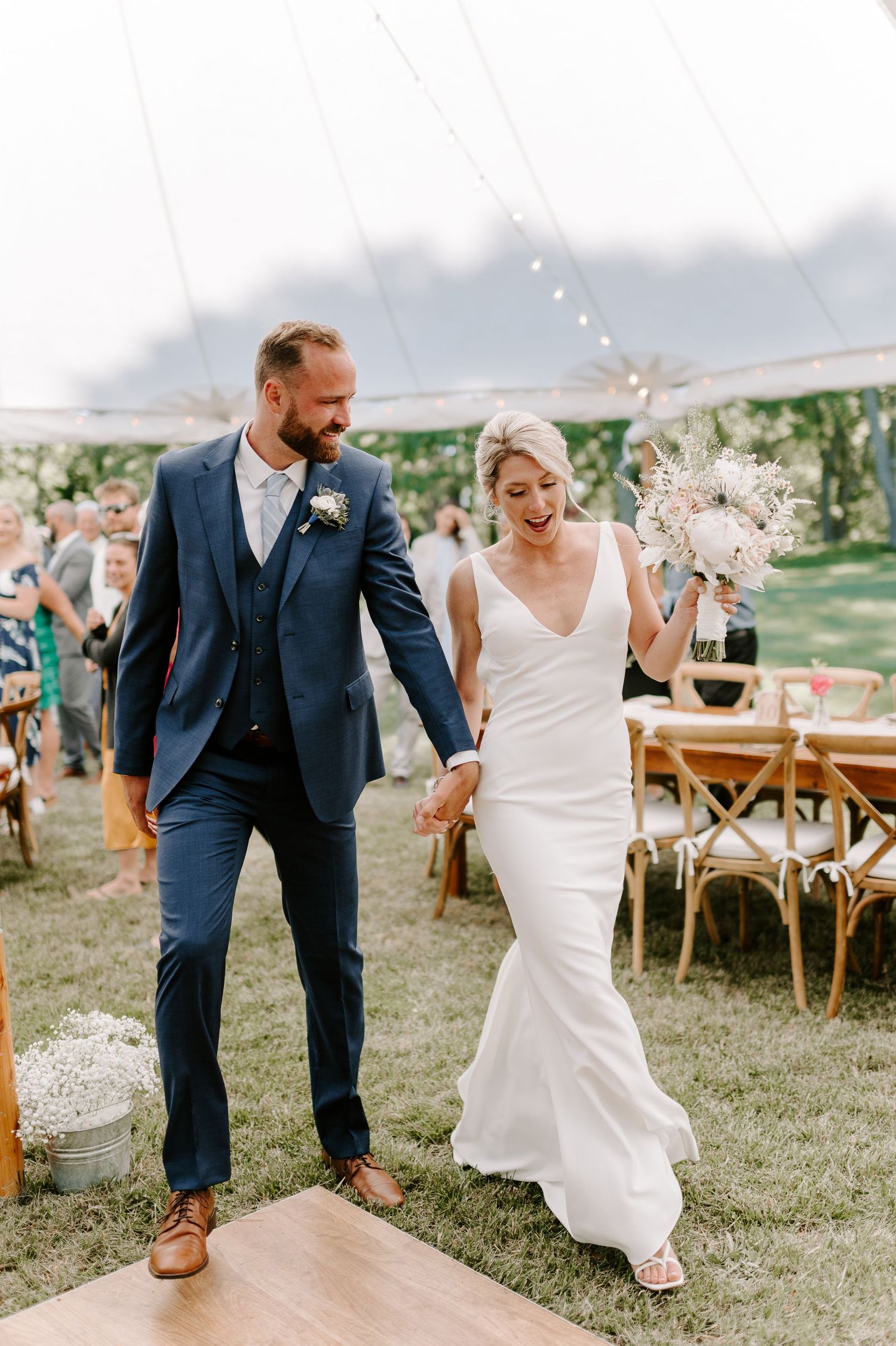 Dancing celebration on a wooden floor under an elegant white tent with festive decorations.
