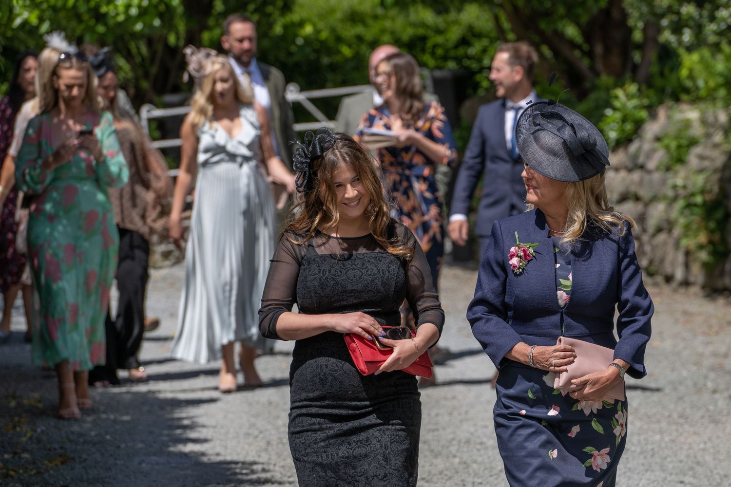 Wedding guests walking along a garden path on a sunny summer day.