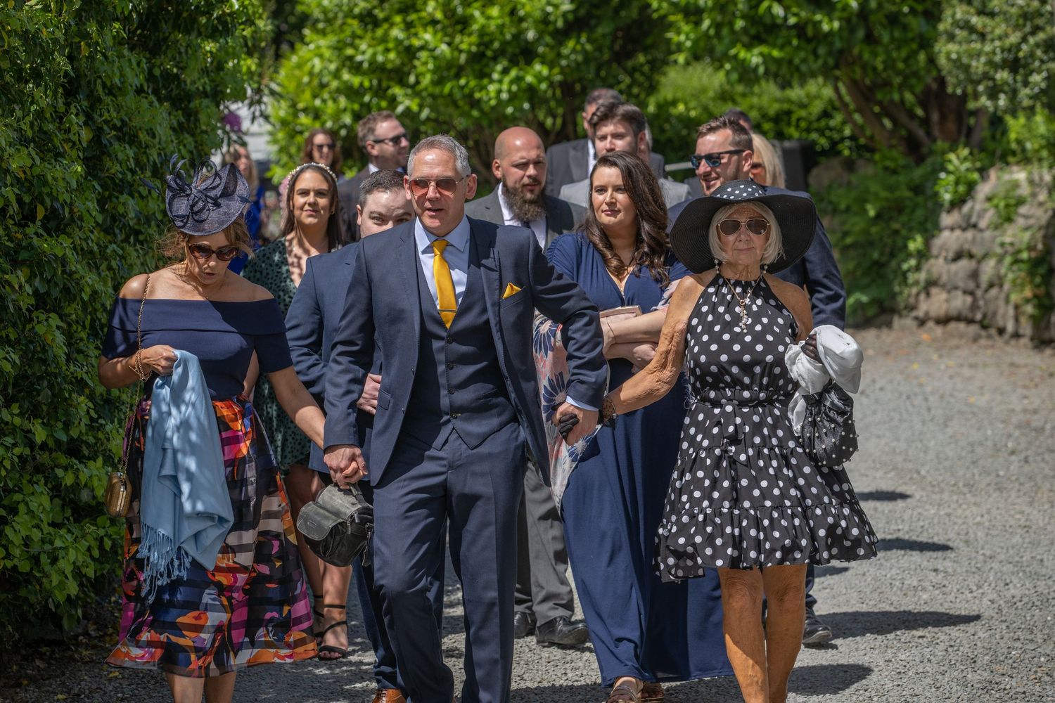 Wedding guests gathered on a stone pathway during an outdoor celebration.