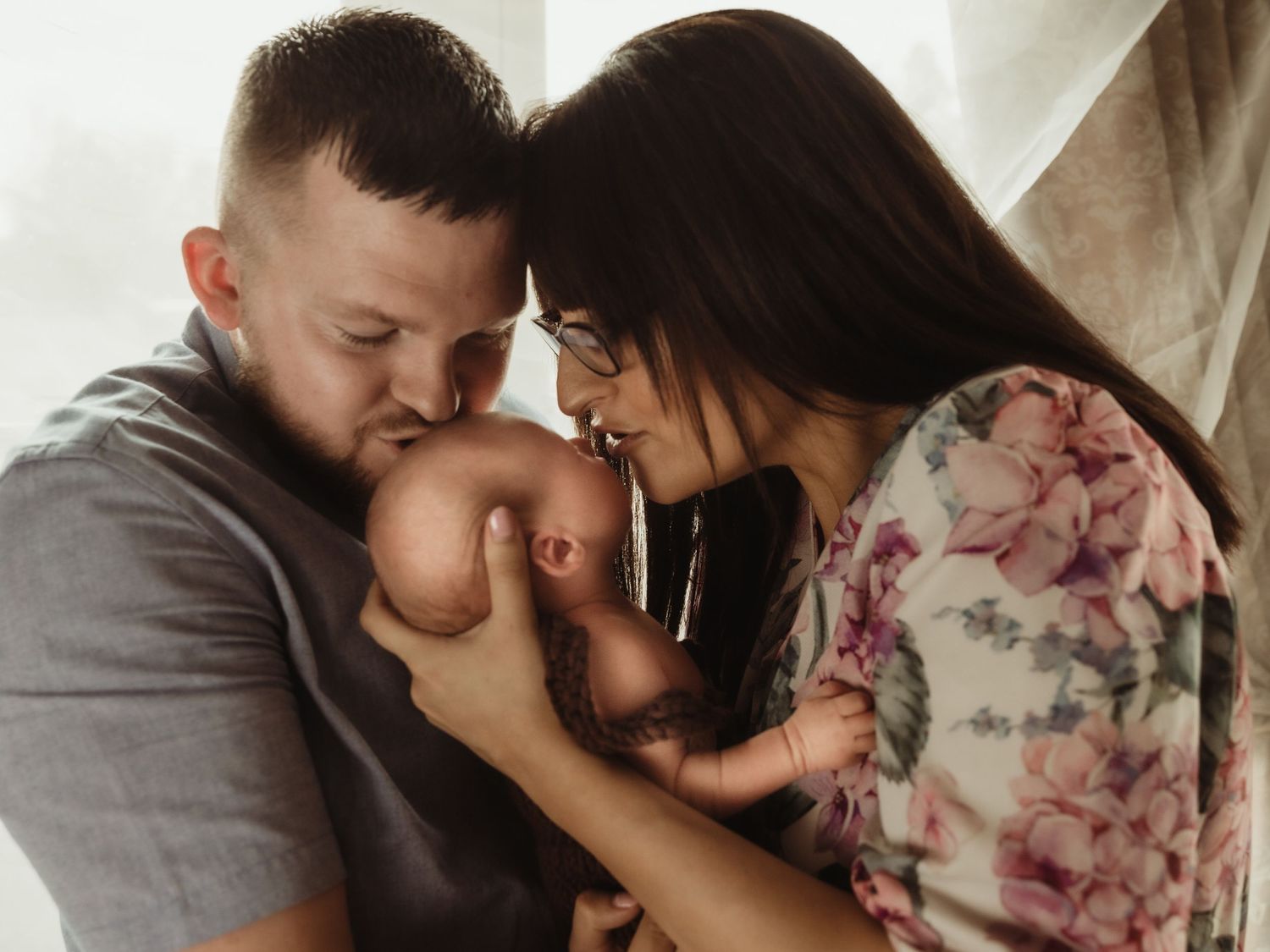 Newborn held by parents. Image by dmcgphoto.