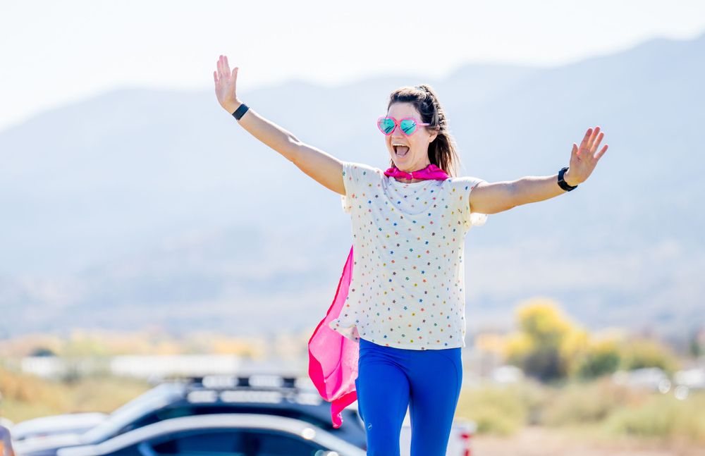 Enthusiastic participant celebrates with arms raised at outdoor running event.