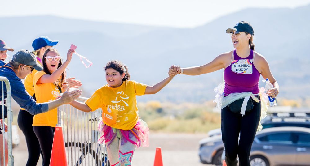Participants high-five each other during outdoor running event with mountains in background.