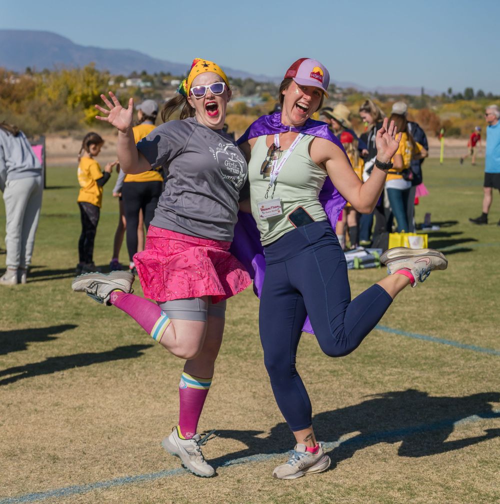 Two enthusiastic participants jumping and celebrating at outdoor festival event.