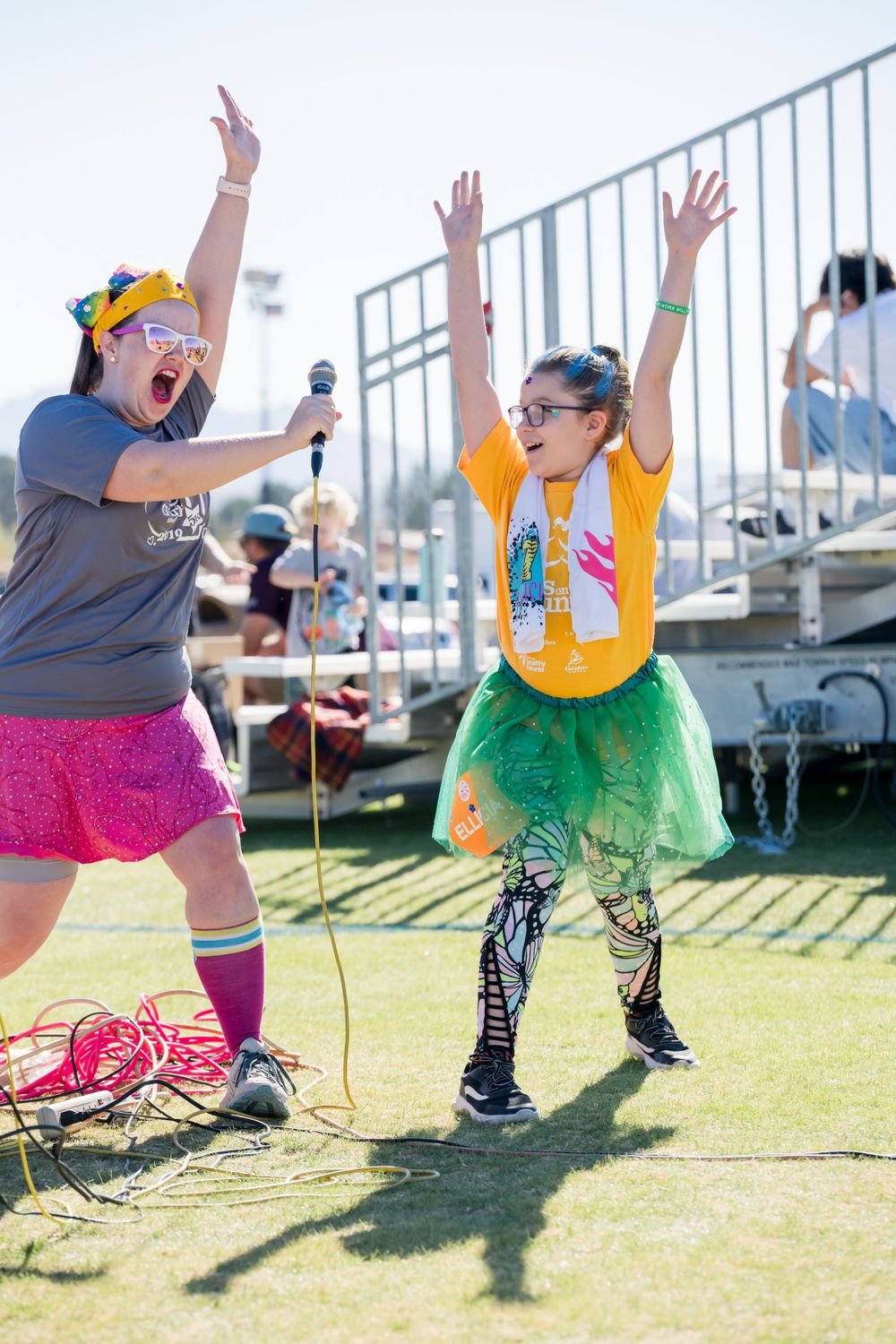 Two participants in colorful outfits dancing enthusiastically at outdoor event.