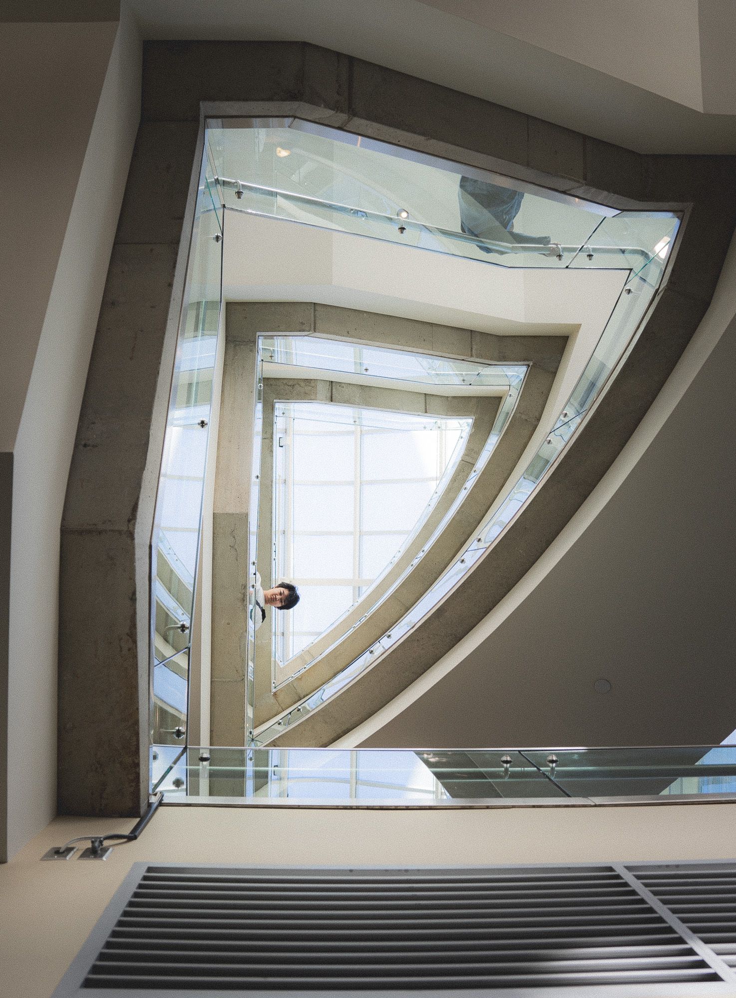 A man looking down from the railings of a staircase, architectural photography.
