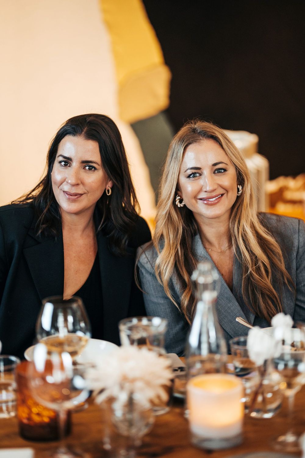 Two friends enjoying dinner and wine at elegant table setting with candlelight.