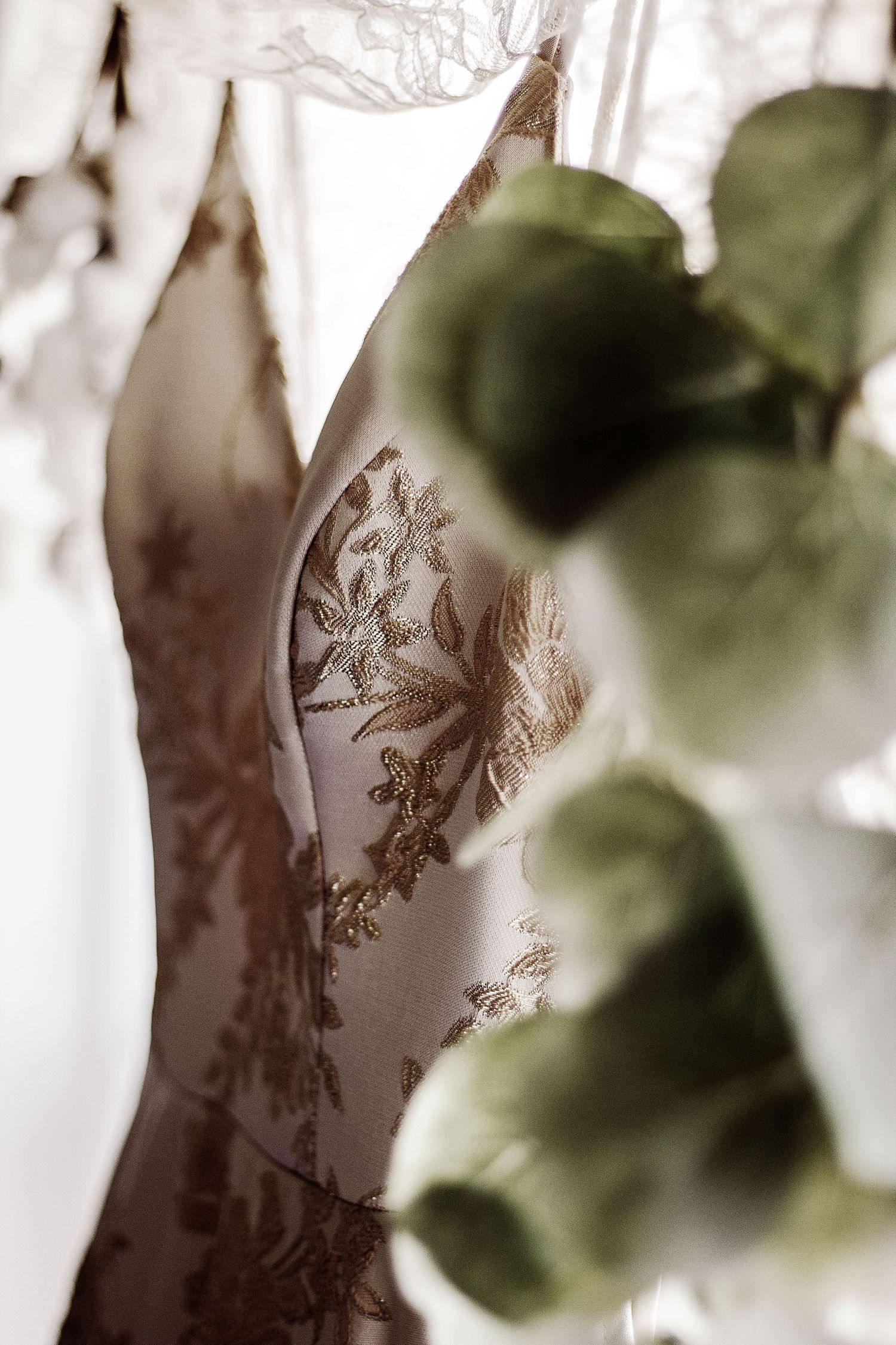 Close-up detail of delicate lace floral embroidery on white wedding dress fabric.