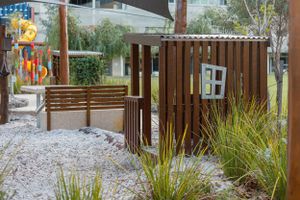 Wooden fenced play area with decorative elements and landscaping in garden setting.