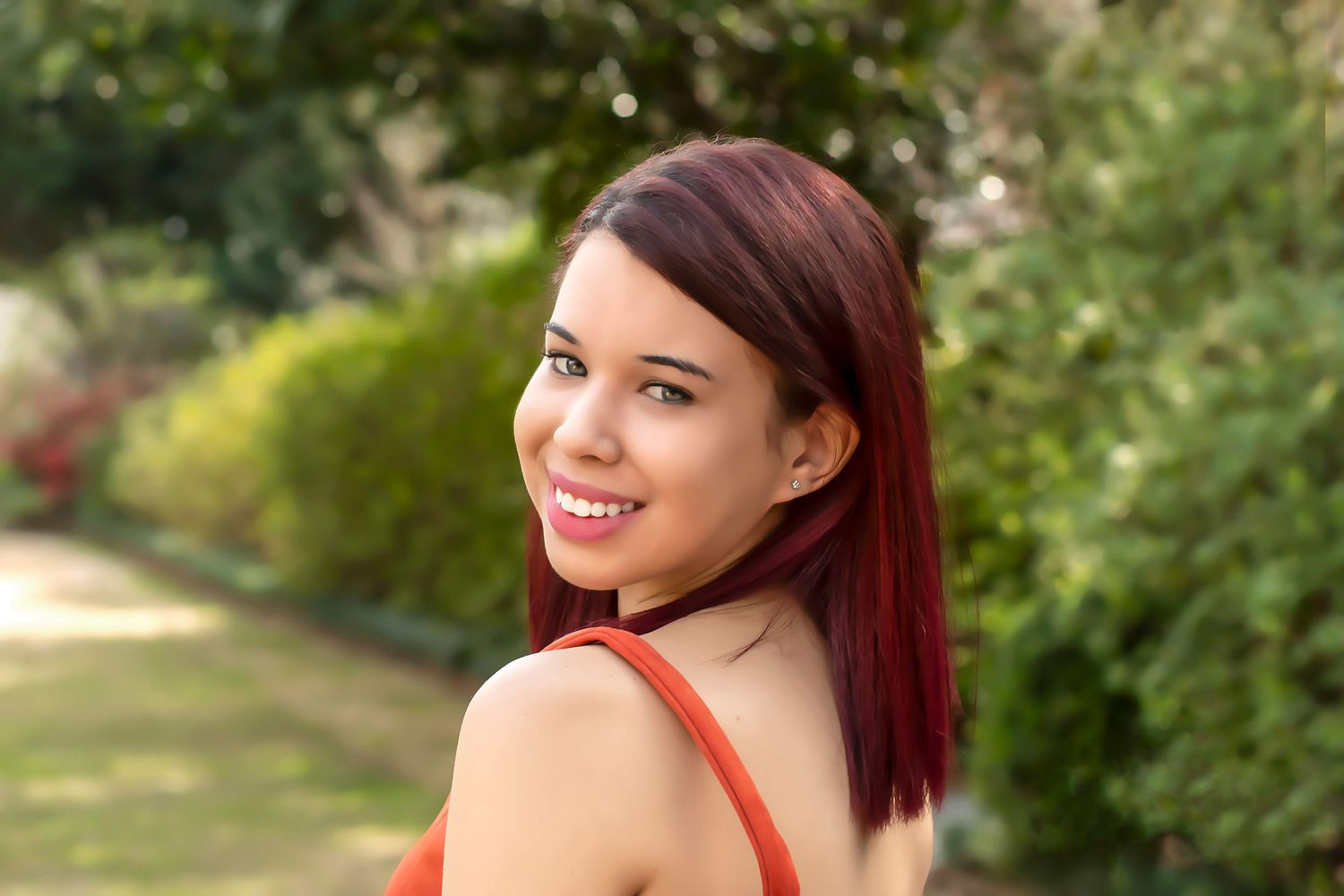 Summer portrait series featuring red top against lush garden background.