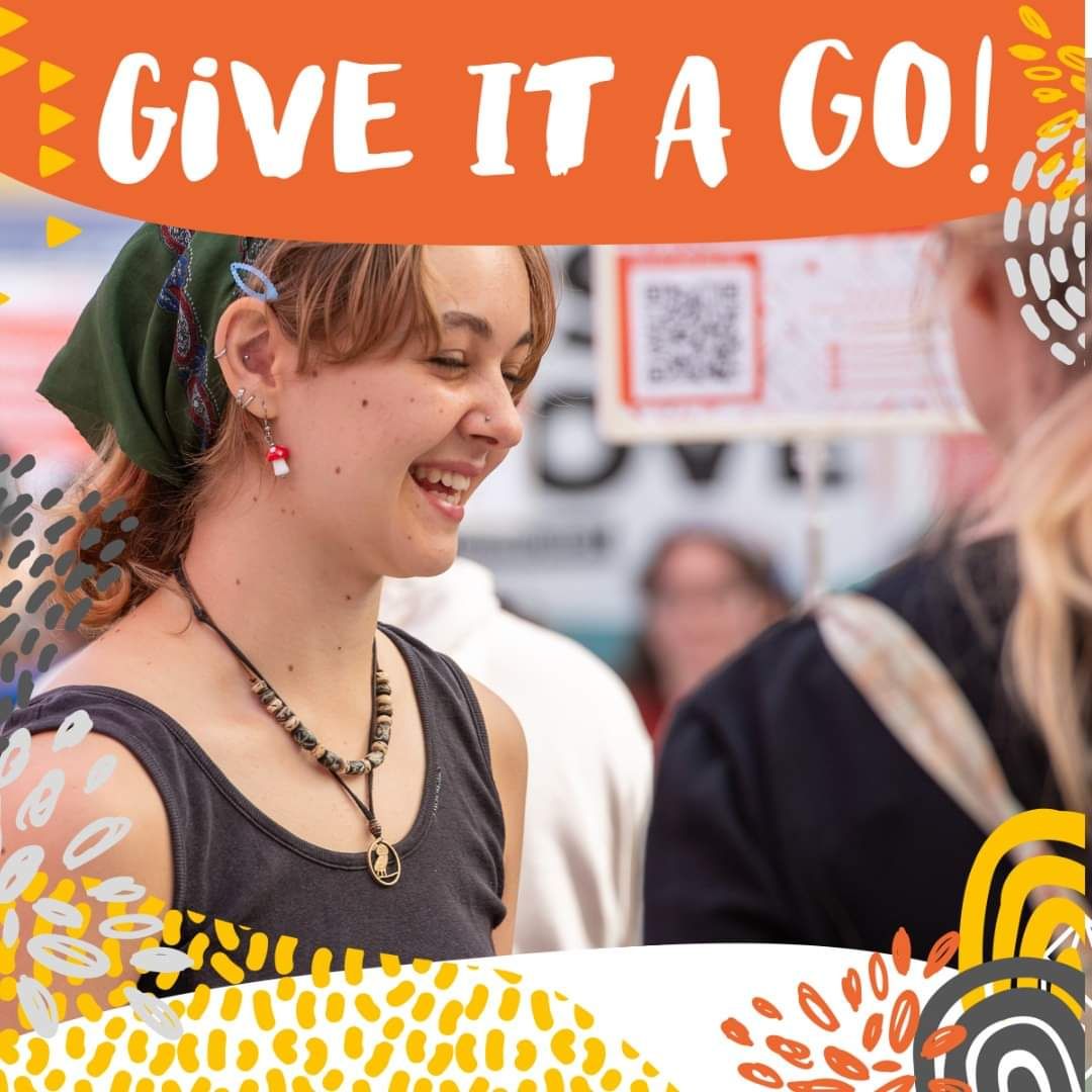 Student smiling during a lively social event with decorative orange banner.