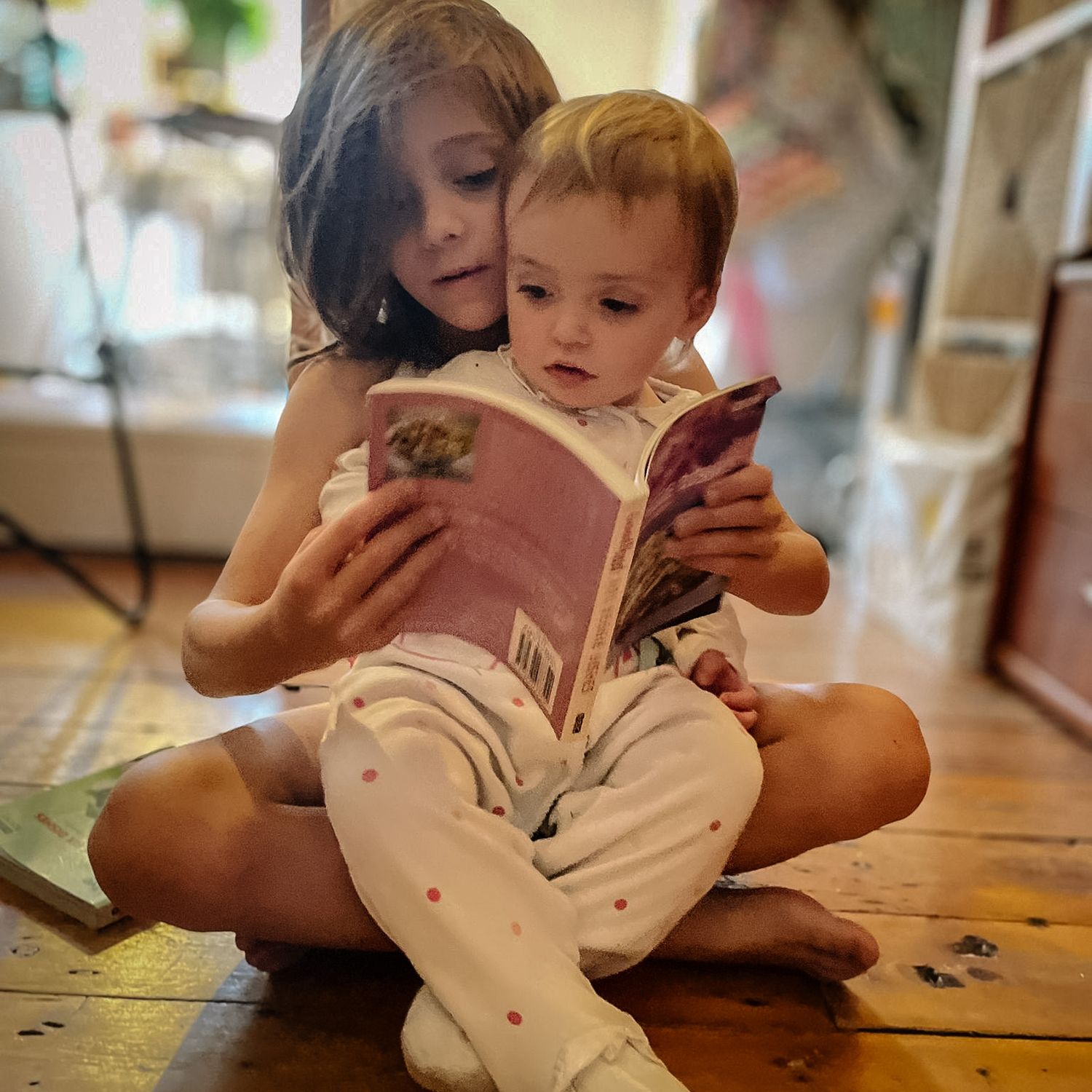 A tender moment of reading together on the floor, sharing a book and creating early literacy memories.