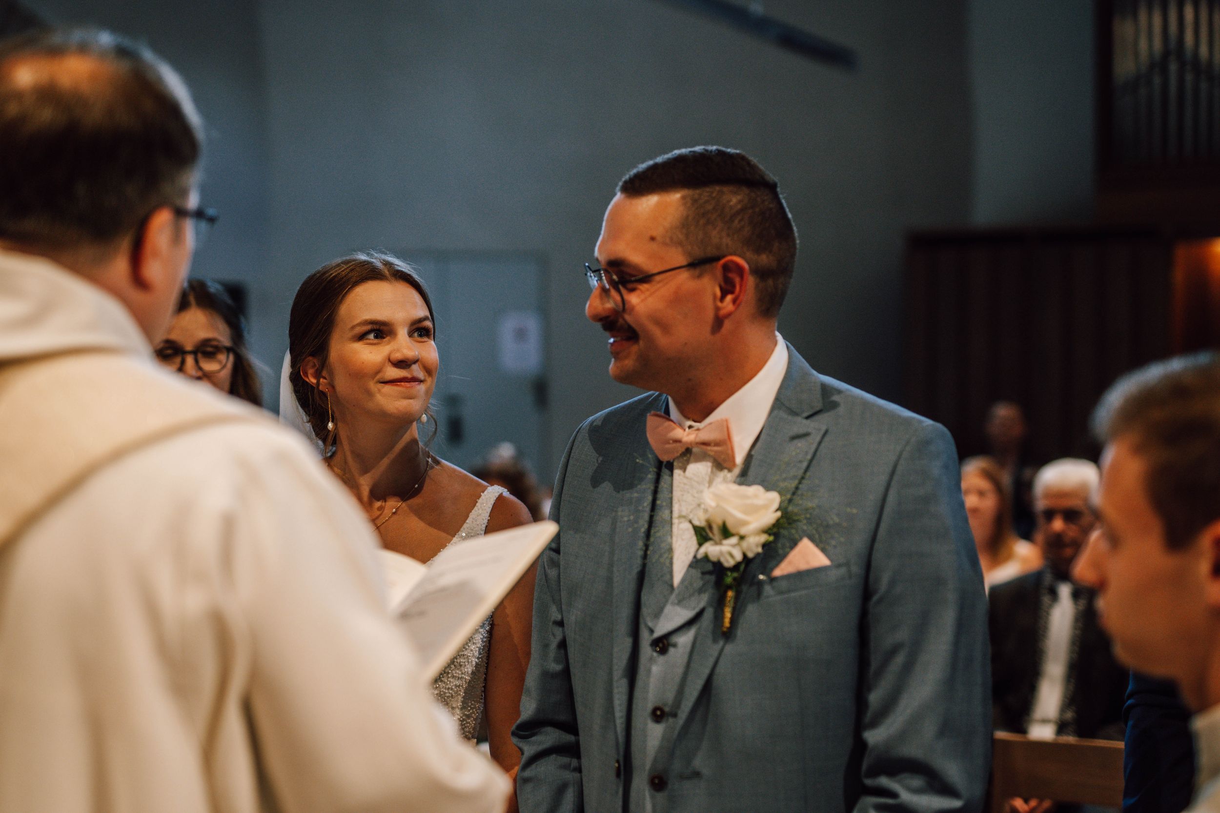 A wedding ceremony moment captured in a church with warm lighting.