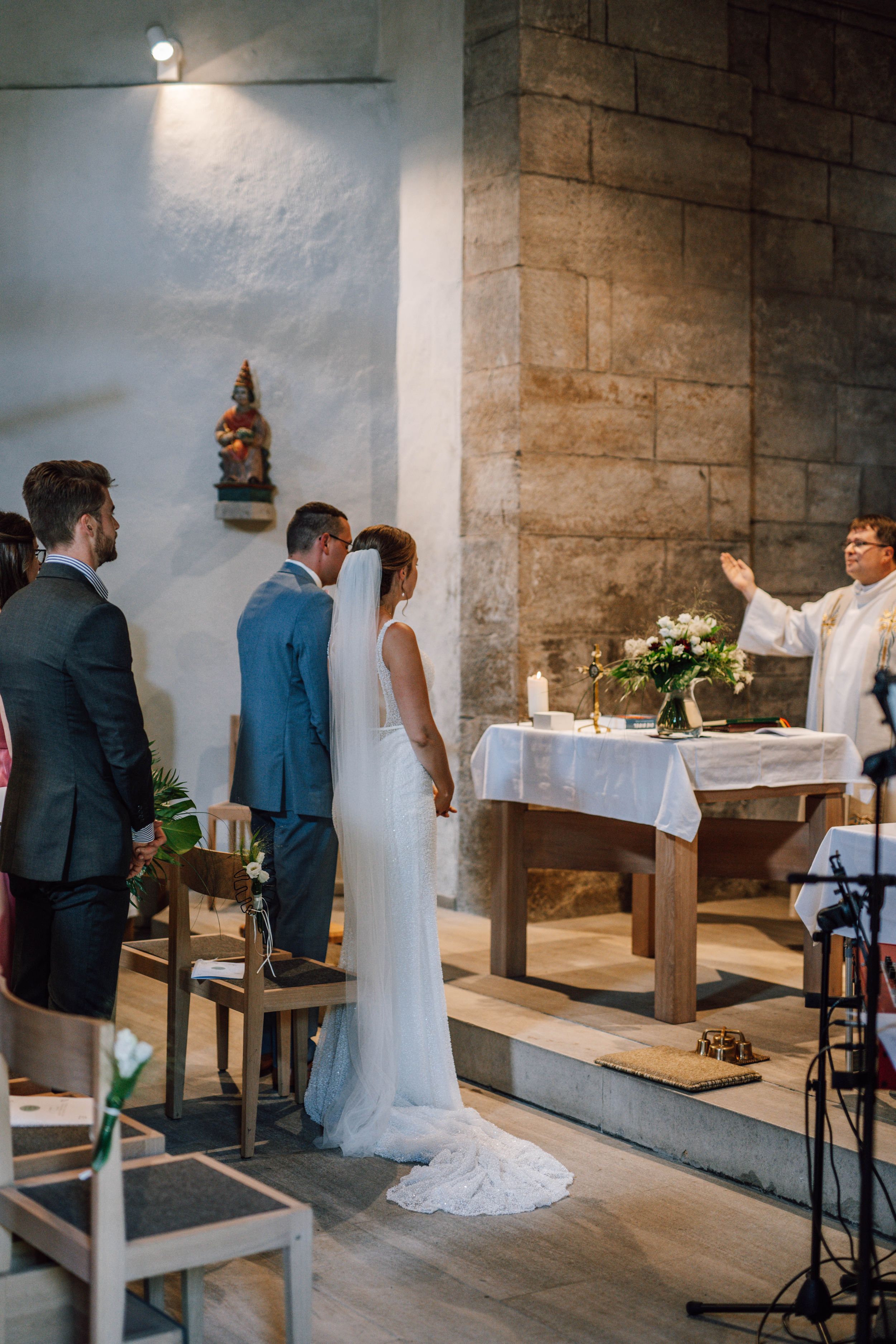 Traditional church wedding ceremony with priest at altar and flowing white wedding dress.