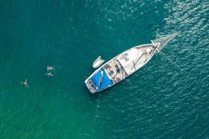Aerial view of yacht anchored in crystal clear turquoise waters.