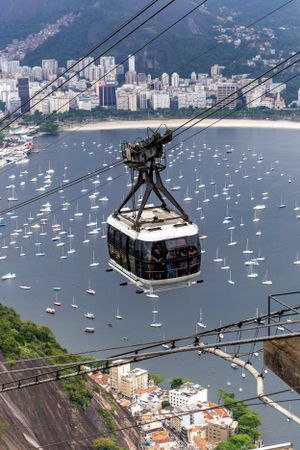Cable car over Guanabara Bay in Rio with sailboats and city skyline in background.