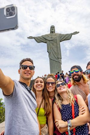 Tourists taking group photo in front of Christ the Redeemer statue in Rio de Janeiro.