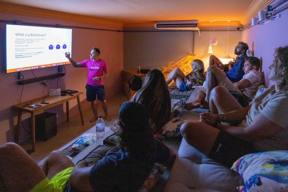 Audience watching a presentation in a dimly lit room with projector screen.