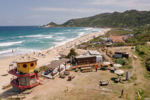 Aerial view of a beach bar and surfing spot with colorful shacks along the coastline.