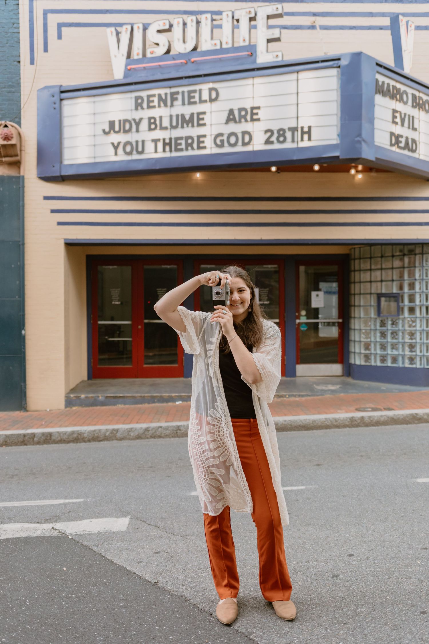 Photographer, Molly, taking a photo in front of the Visulite Movie Theatre in Downtown Staunton