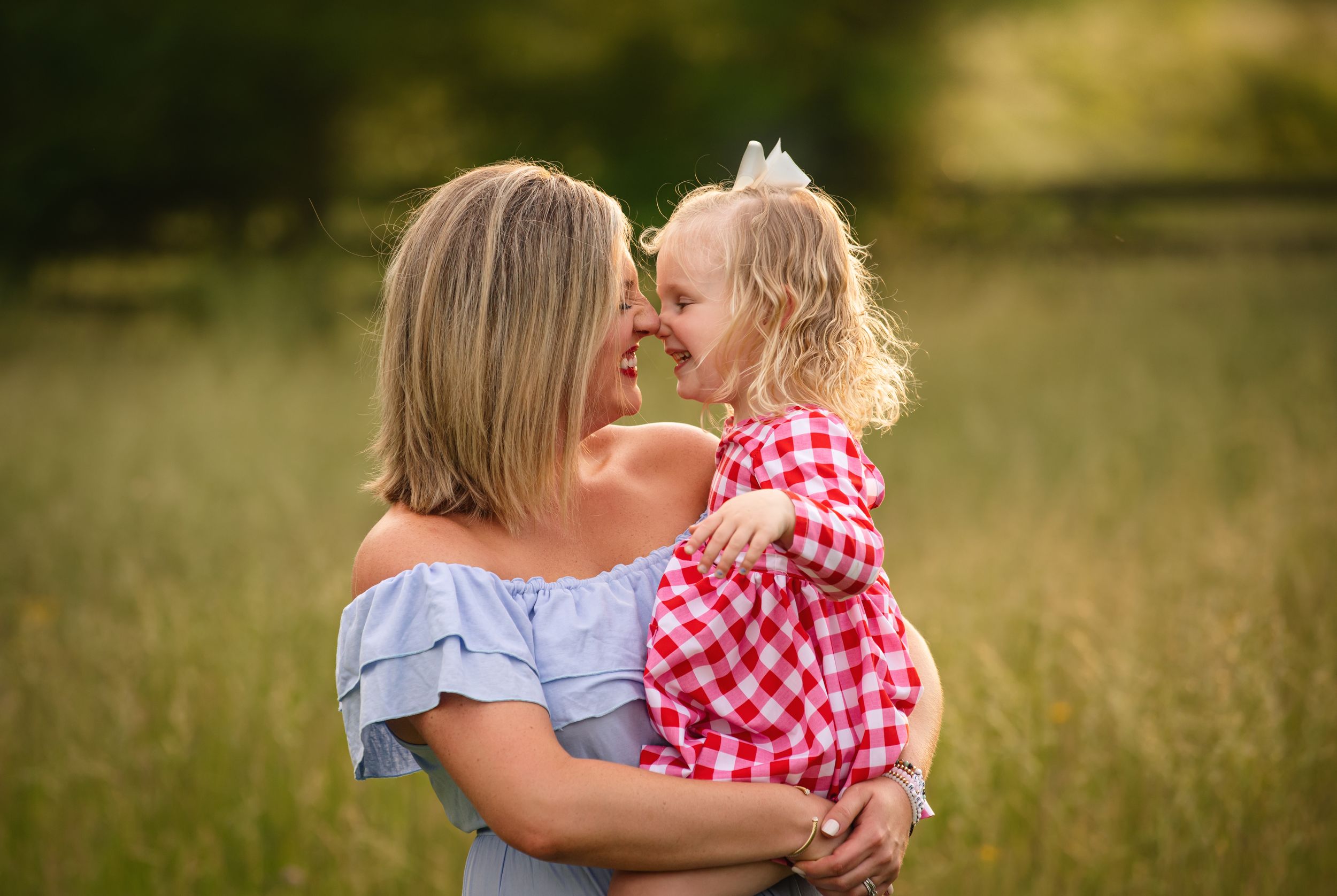 Mother and daughter share a joyful moment together in a sunny field during golden hour.