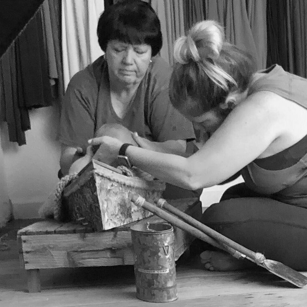 Vintage black and white photograph of two people examining an antique tool.
