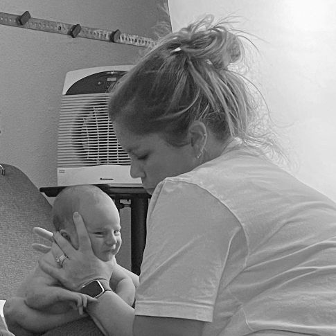 Black and white candid moment of infant care in natural home setting.